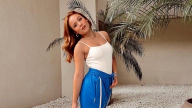 Larissa Manoela de camisa branca e calça azul inclinada 