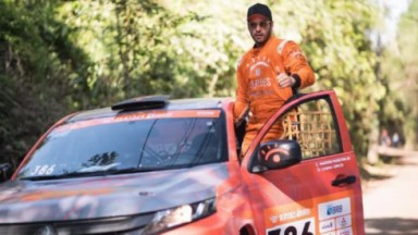 Leandro Lima com macacão laranja em carro laranja 