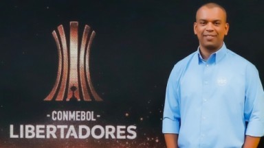 Luiz Alano ao lado de telão com o logo da Conmebol Libertadores 