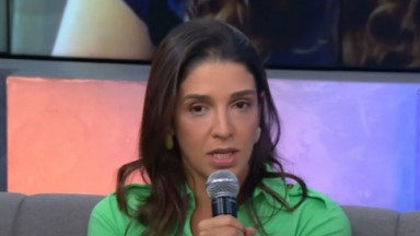 Ana Carolina Oliveira de cabelo solto e camisa verde, falando em microfone 
