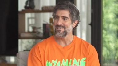 Marcos Mion de camiseta laranja em entrevista para o Fantástico 