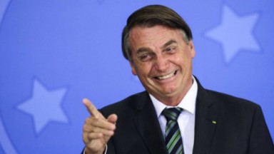 Jair Bolsonaro apontando e rindo 