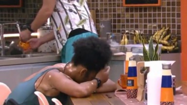 Natália Deodato chorando com a cabeça apoiada na mesa da cozinha da xêpa 