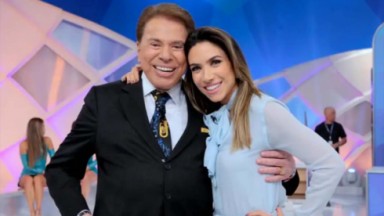Silvio Santos posado sorridente com Patrícia Abravanel em estúdio de programa 