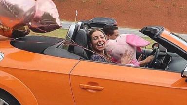 Paula em carro conversível laranja 
