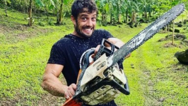 Rafael Cardoso sorridente com uma motoserra na mão 