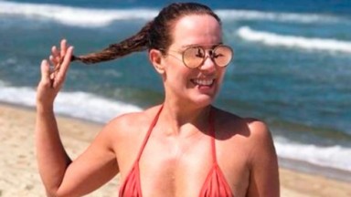Regina Volpato na praia mexendo no cabelo 