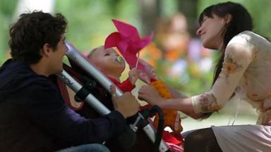 Cena de A Vida da Gente com Julia no carrinho de bebê, e Rodrigo e Manu frente a frente sorrindo 