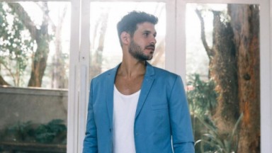 Rodrigo Mussi de camiseta branca e paletó azul posando para foto 