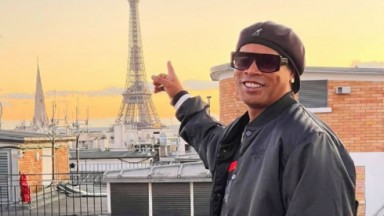 Ronaldinho Gaúcho em Paris, na França. com a torre Eiffel ao fundo, de óculos escuros, boina e sorridente 