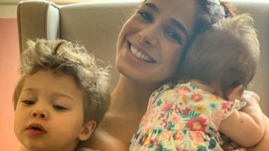 Sabrina Petraglia sorridente com os filhos, Gael e Maya, no colo 