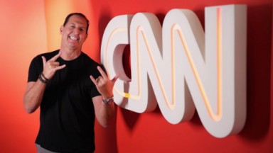 Benjamin Back sorrindo e gesticulando em corredor da CNN 