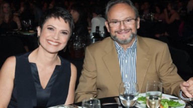 Sandra Annenberg e Ernesto Paglia  sorridentes em uma mesa de jantar 
