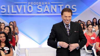 Silvio Santos com sua tradicional gargalhada abotoando o terno 