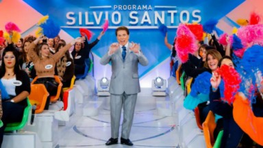 Silvio Santos no meio da plateia de terno prateado 