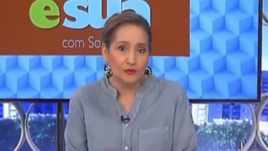 Sonia Abrão no A Tarde é Sua, de camisa cinza e cabelo preso, falando com expressão séria 