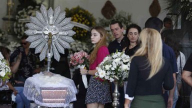 Susana Naspolini no caixão com algumas pessoas próximas, incluindo a filha, Julia, com flores nas mãos 