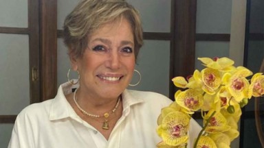 Susana Vieira posada ao lado de orquídea amarela 