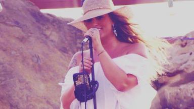 Taylor Dee cantando com microfone 