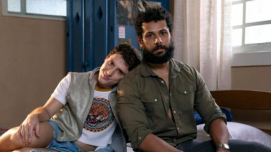 Diego Martins e Amaury Lorenzo como Kelvin e Ramiro, sentados em cama de cenário 