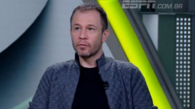  Tiago Leifert de camisa preta e casaco cinza no cenário do Bola da Vez, da ESPN 