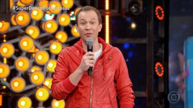 Tiago Leifert de jaqueta vermelha segurando microfone 