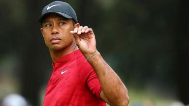 Tiger Woods de semblante sério fazendo sinal com a mão 