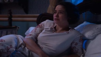  Paloma Duarte, como Heloísa, deitada na cama usando vestido azul em cena de Além da Ilusão  
