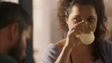 A atriz Isabel Teixeira, como Maria Bruaca, com um copo na boca em cena de Pantanal 