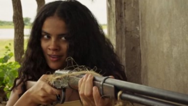 A atriz Bella Campos como Muda apontando arma para Maria Marruá em cena de Pantanal  