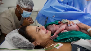 Viviane Araújo chorando com o filho Joaquim nos braços após o parto e Guilherme Militão se emociona e obseeva ao fundo 
