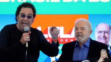 Walter Casagrande discursando segurando microfone ao lado de Lula 