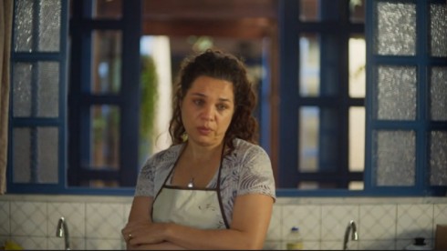 Maria Bruaca (Isabel Teixeira) de avental e braços cruzados em cena na cozinha para a novela Pantanal