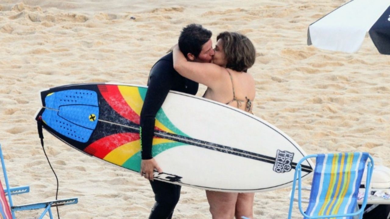 Adriane Bonato e Claudia Rodrigues se beijando, em pé na areia de praia carioca