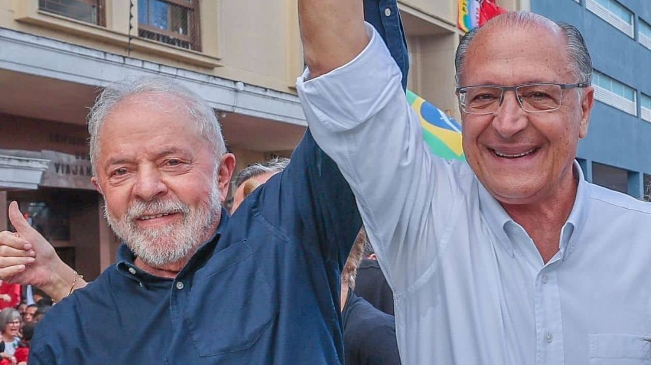 Lula e Geraldo Alckmin sorrindo com os braços para o alto