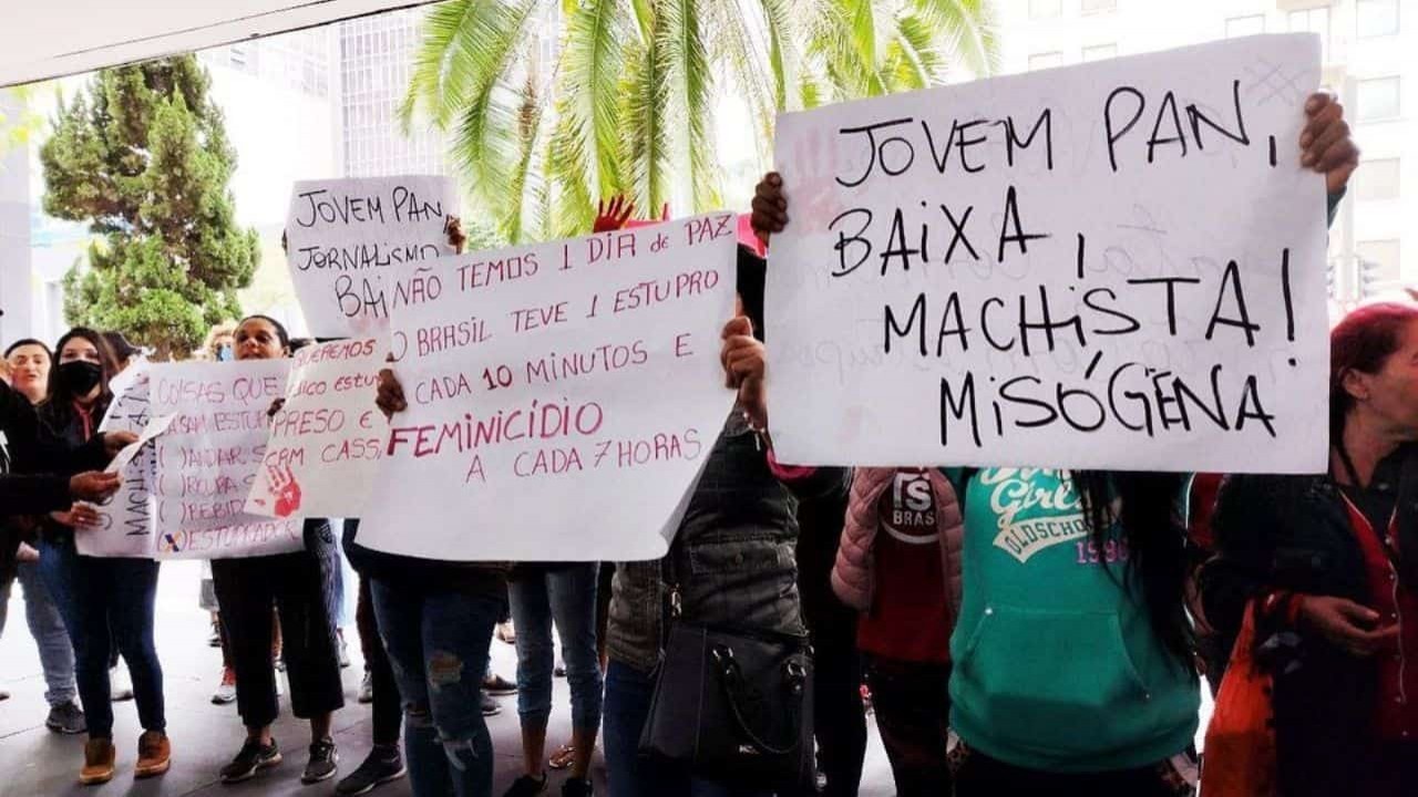 Mulheres com cartazes protestando no prédio da Jovem Pan