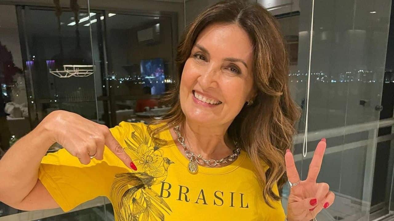 Fátima Bernardes sorrindo com camisa do Brasil e fazendo sinal de 
