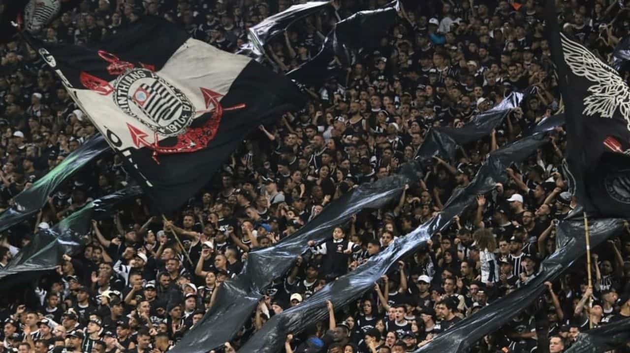 Torcida do Corinthians com bandeiras e uniforme