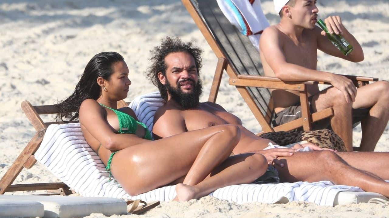 Laís Ribeiro e marido deitados em espreguiçadeira na praia