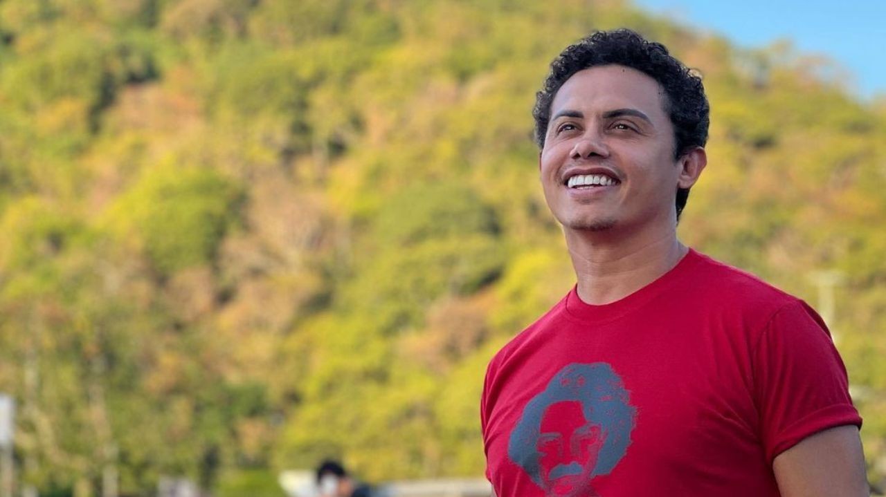 Silvero Pereira olhando para cima, sorrindo, de camiseta vermelha