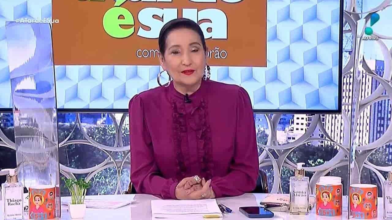 Sonia Abrão no cenário do A Tarde É Sua, de roupa roxa e coque