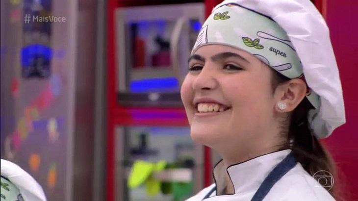 Raphaela Alvitos vestida de chef de cozinha, sorrindo após o anúncio de que ela venceu o Super Chefinhos