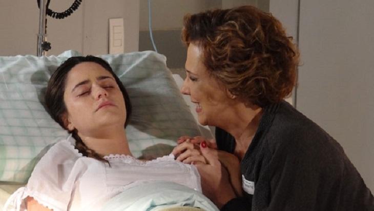 Cena de A Vida da Gente com Ana deitada no hospital e Eva segurando a mão dela e chorando