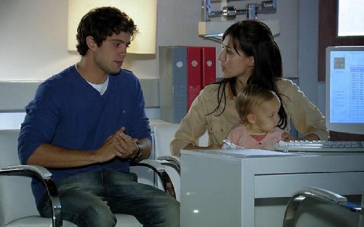 Cena de A Vida da Gente com Rodrigo e Manu sentados, olhando um para o outro e ela com Julia no colo