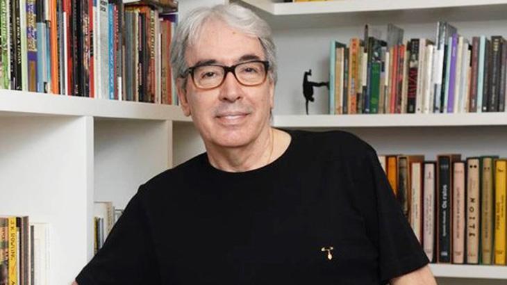 Alcides Nogueira posa para foto à frente de um armário de livros