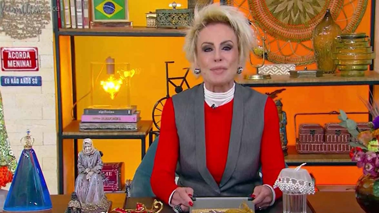 Ana Maria Braga ao vivo na Globo de blusa vermelha e colete cinza