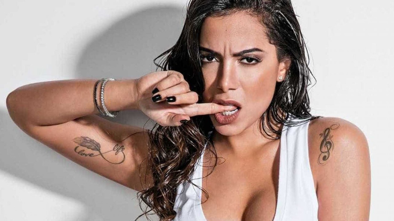 Anitta posada sexy, com o dedo na boca 