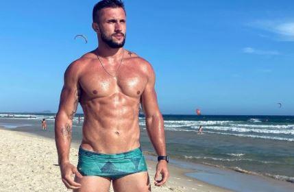 Arthur Picoli posa sem camisa em frente à praia 
