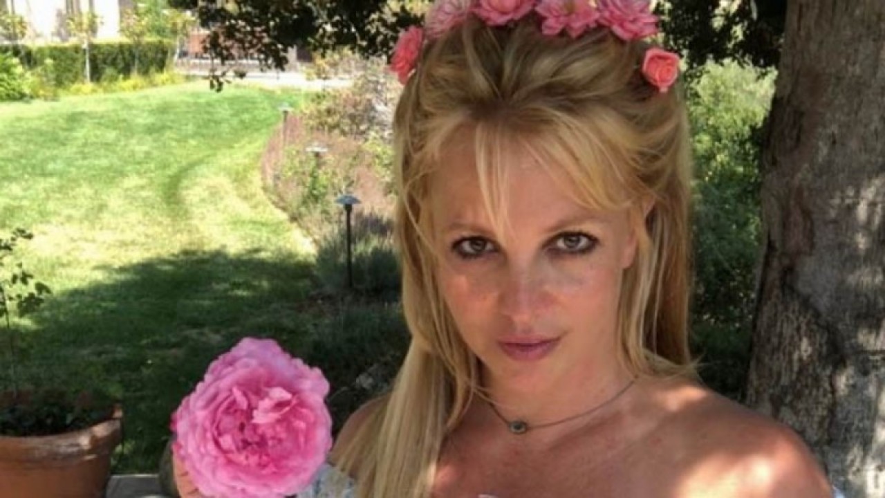 Britney Spears com coroa de flores na cabeça e flor rosa
