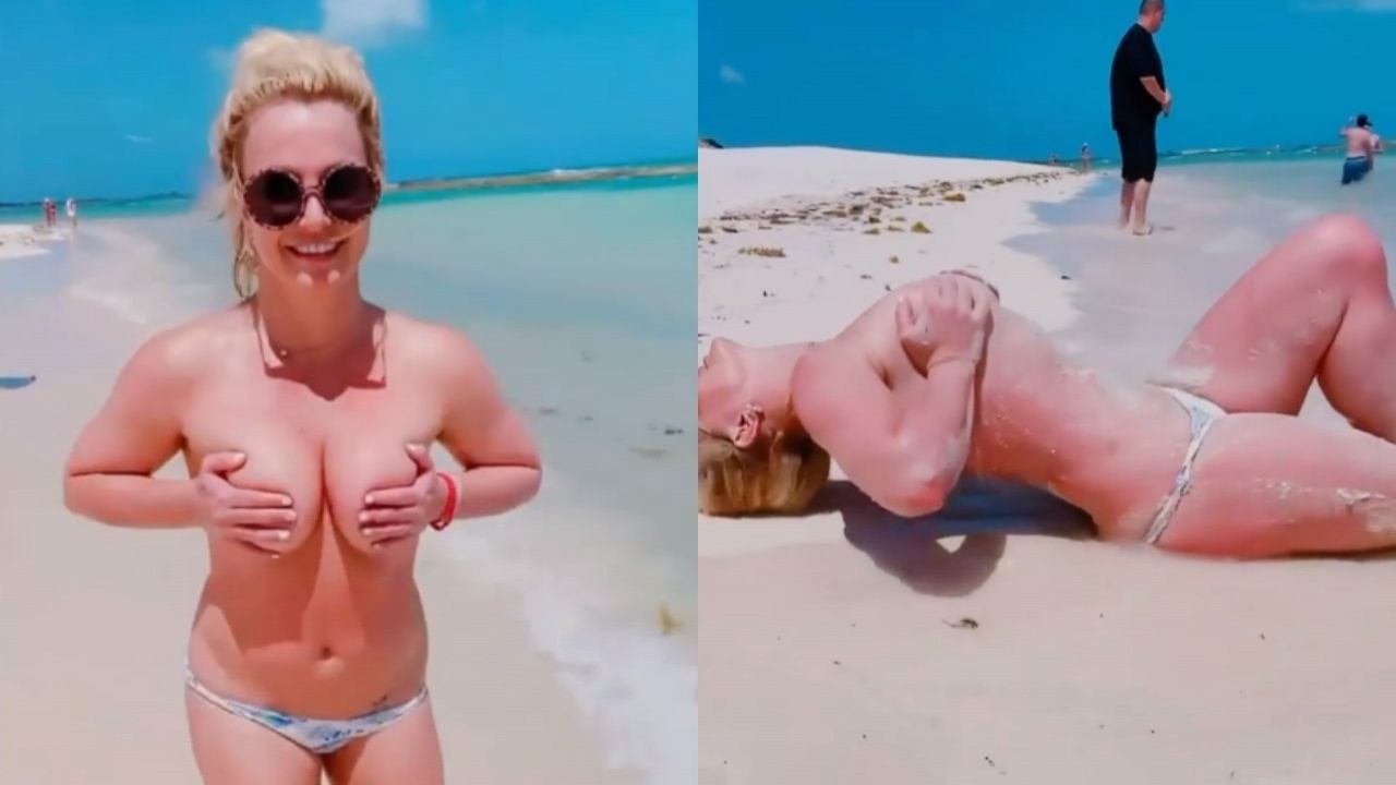 Britney Spears cobrindo os seios com as mãos em praia